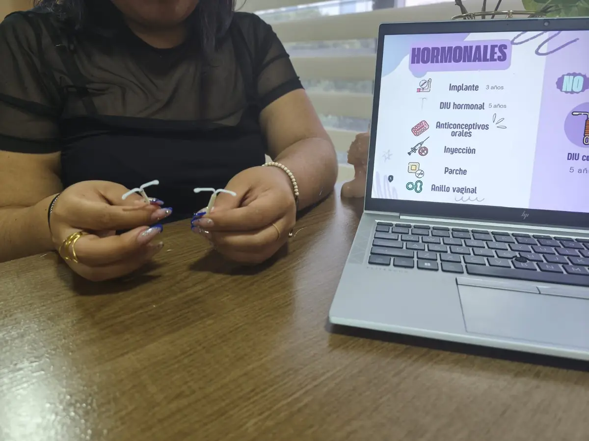 Paciente con un dispositivo intrauterino en las manos, junto a la presentación de métodos hormonales