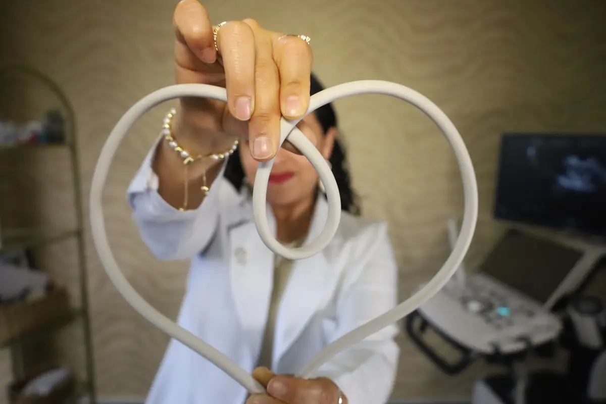 La Dra. Lidia Chávez formando un corazón con el cable del transductor de ultrasonido